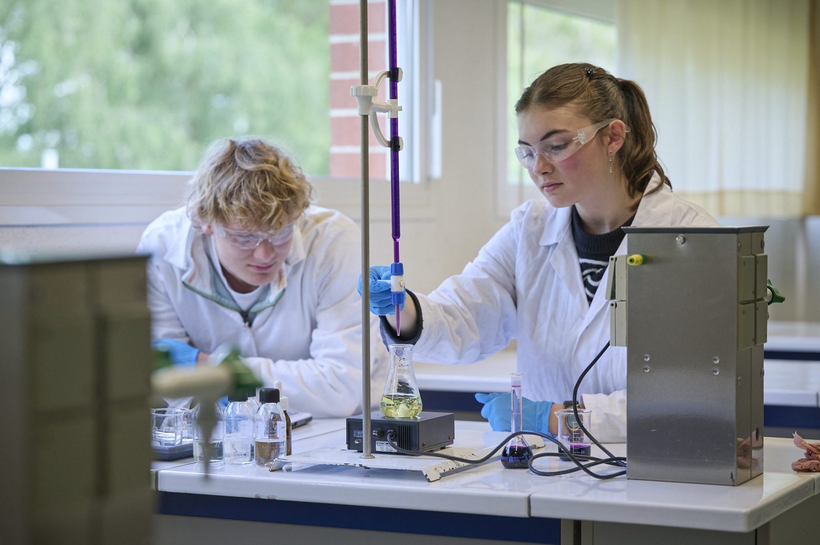 Travaux pratiques de chimie Deux lycéens en blouse réalisent un titrage en chimie